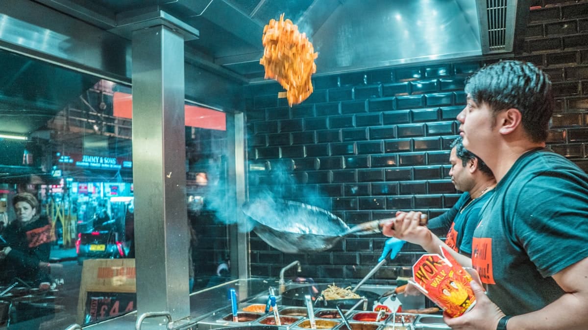 Cuisinier au wok sous les néons du restaurant, ambiance nocturne