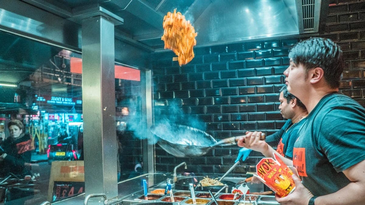 Cuisinier au wok sous les néons du restaurant, ambiance nocturne